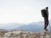 traveler hiking mountains while having his essentials backpack